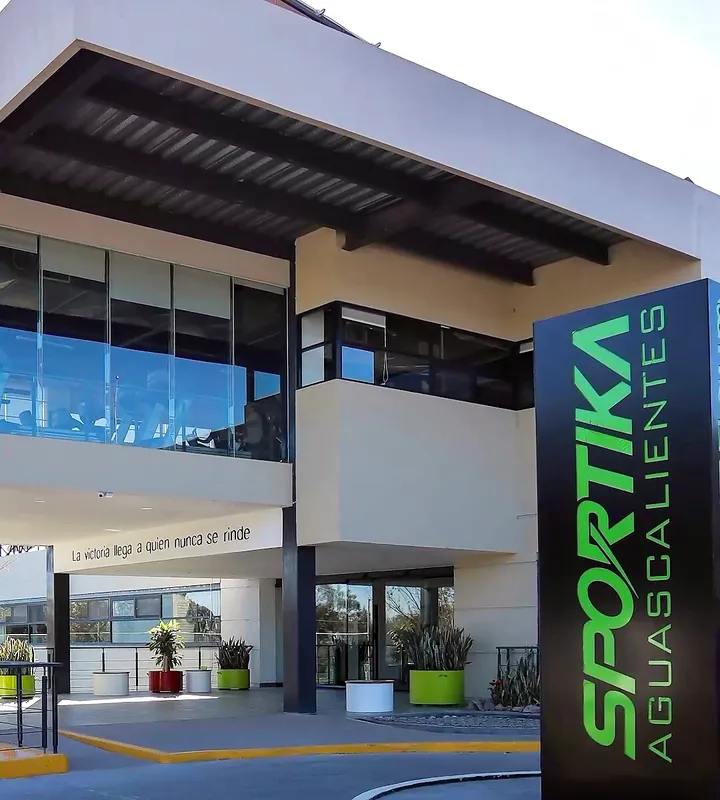 Entrada principal de Club Sportika con su monolito verde